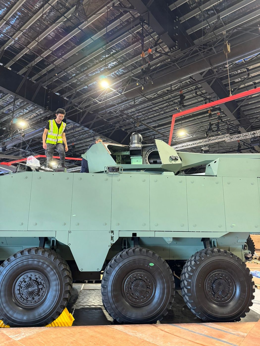 A Legion maker standing on top of a large fabricated vehicle build in the hall