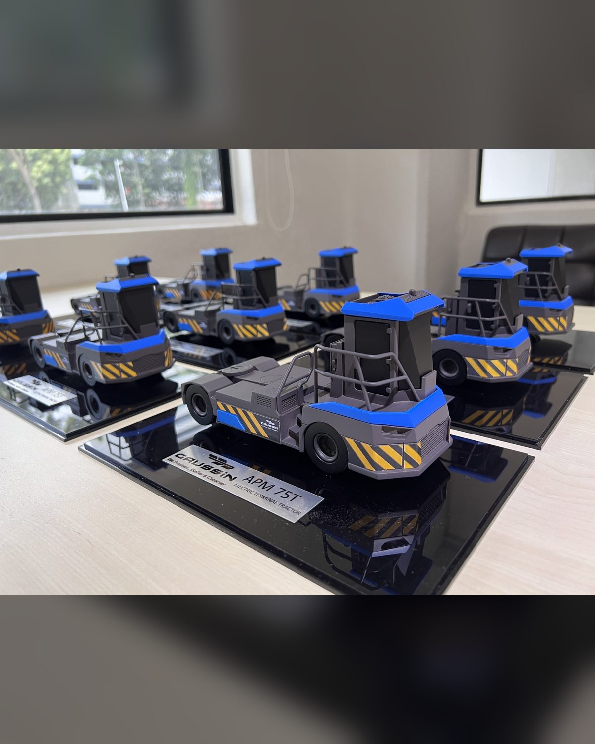 Detailed desktop scale models of the Gaussin APM 75T autonomous vehicle on branded nameplate bases