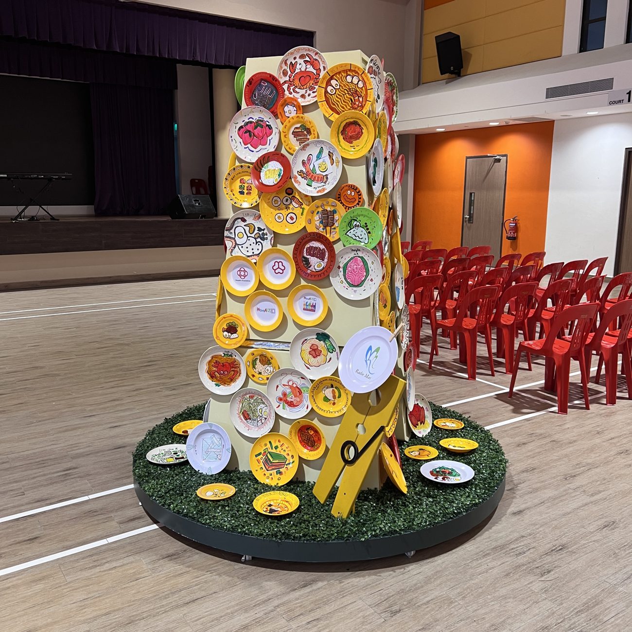 Giant wooden clothes-peg sculpture studded with plates hand-painted by Radin Mas residents, built with Saltt Workshop